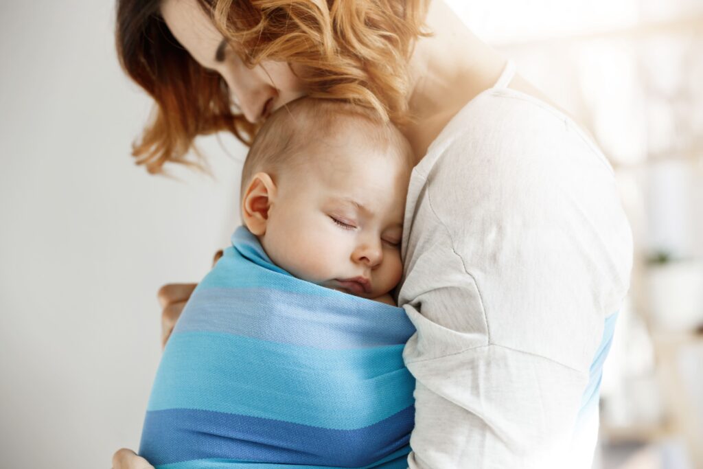 Bebé dormido en brazos de su madre durante la noche, mostrando cómo mi bebé no duerme sin contacto físico